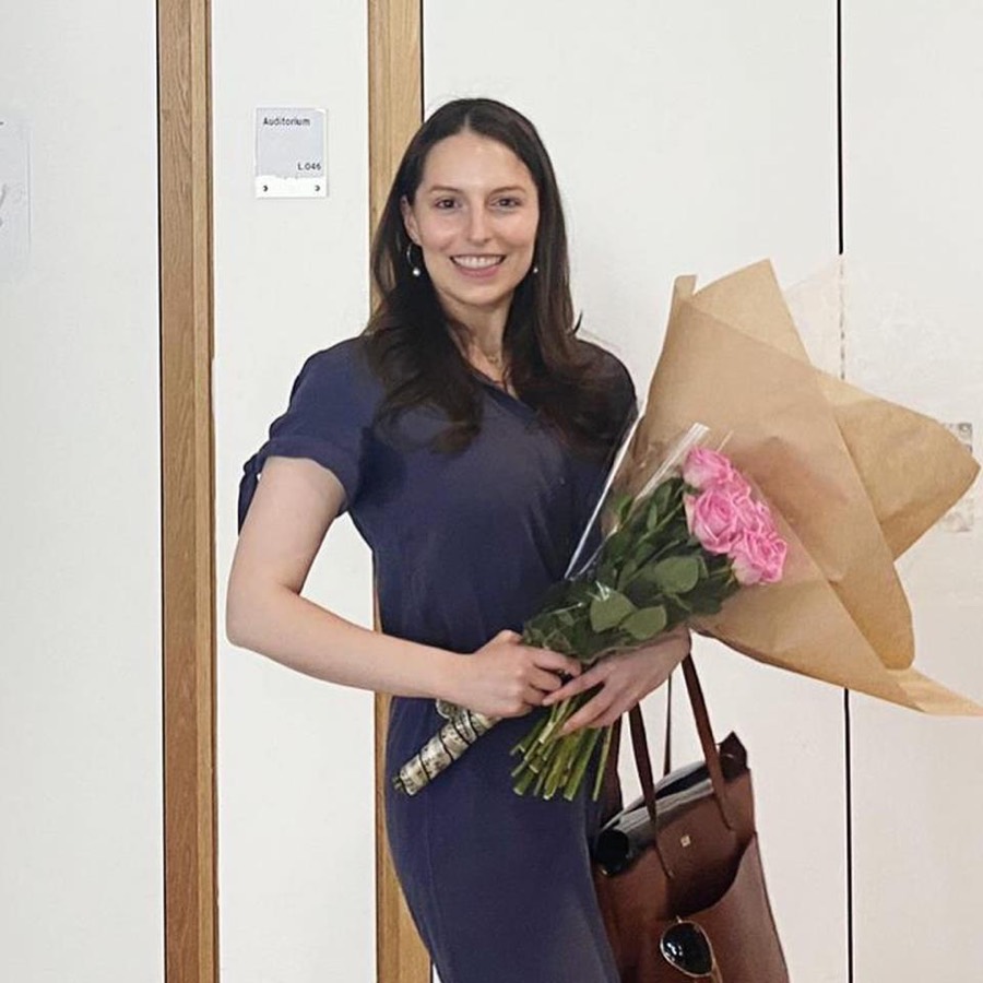 Kelsey Hopper holding a bouquet of flowers outside an auditorium